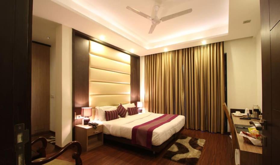 古尔冈Indiyaah Inn的一间卧室配有一张床、一张书桌和一个窗户。