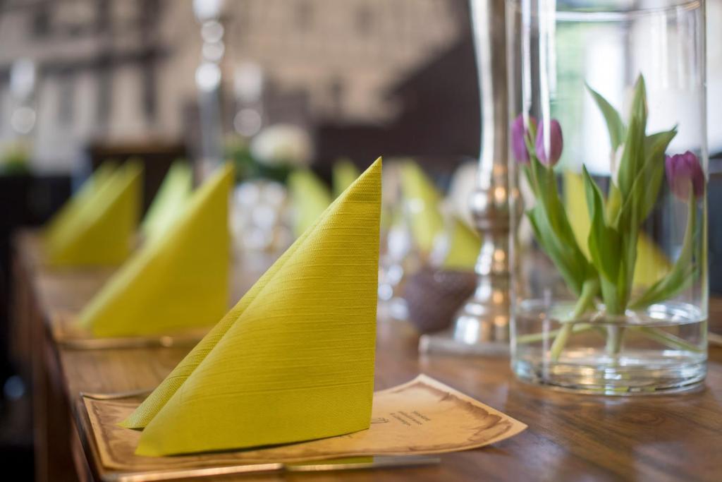 富尔达莱比锡霍夫酒店的一张带黄色餐巾的桌子和一个花瓶