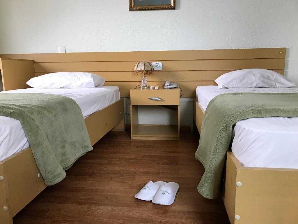 圣保罗全家酒店的客房设有两张床和一张带床头柜的桌子。