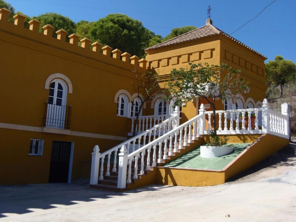 博尔诺斯Hostal La Parada的黄色的建筑,有楼梯和白色的栅栏