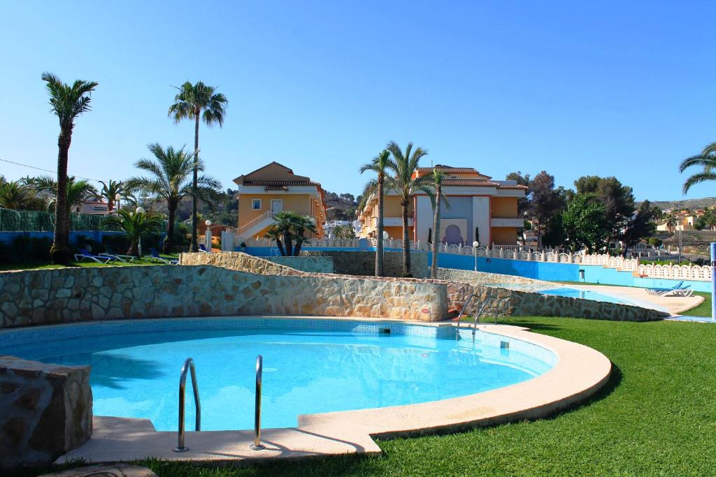 哈维亚巴伊亚皮诺索公寓式酒店的棕榈树和房屋的庭院内的游泳池