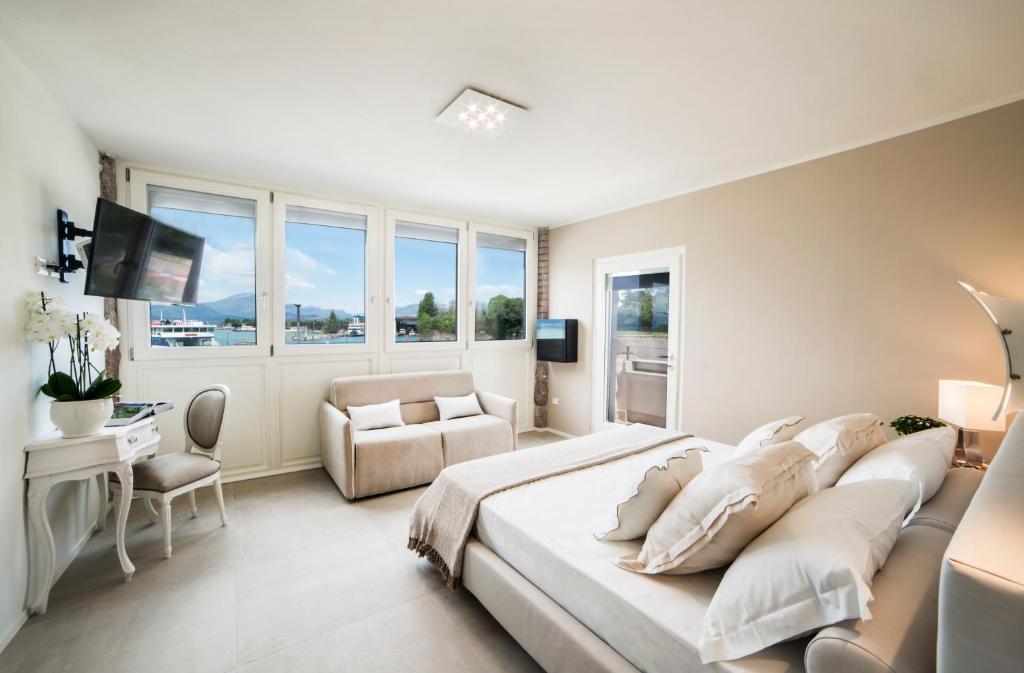 佩斯基耶拉德加达Riviera Carducci Rooms的白色卧室配有一张大床和椅子