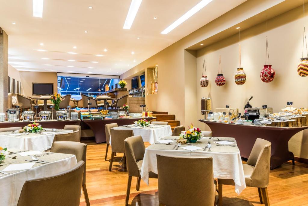 波哥大罗萨莱斯广场酒店的一间设有白色桌椅的用餐室