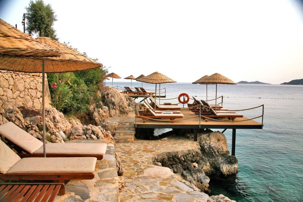 卡尔坎库鲁比酒店的水面上的一个码头上的一组椅子和遮阳伞