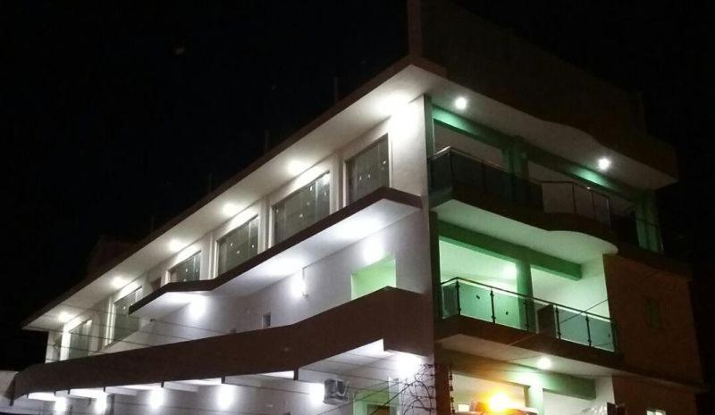 Currais Novos鲍萨达曼克斯酒店的一座晚上有绿灯的建筑