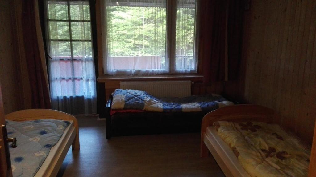 扎沃亚Agroturystyka pod Pstragiem的带2扇窗户的客房内的2张床