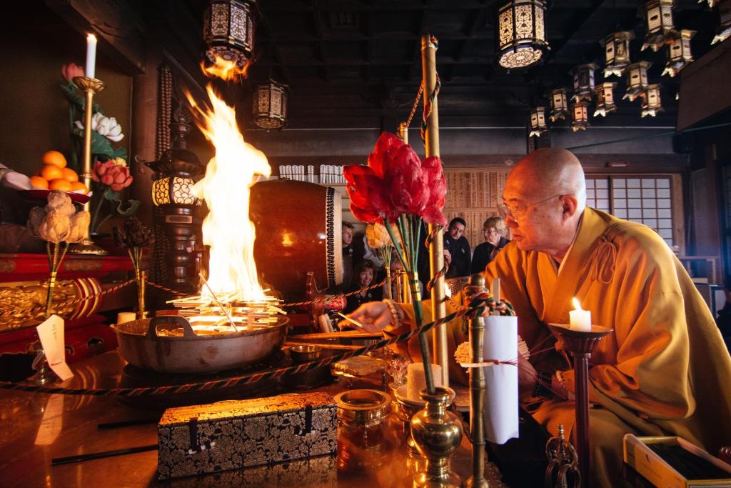 高野山高野山 宿坊 熊谷寺 -Koyasan Shukubo Kumagaiji-的坐在壁炉间桌子上的僧侣