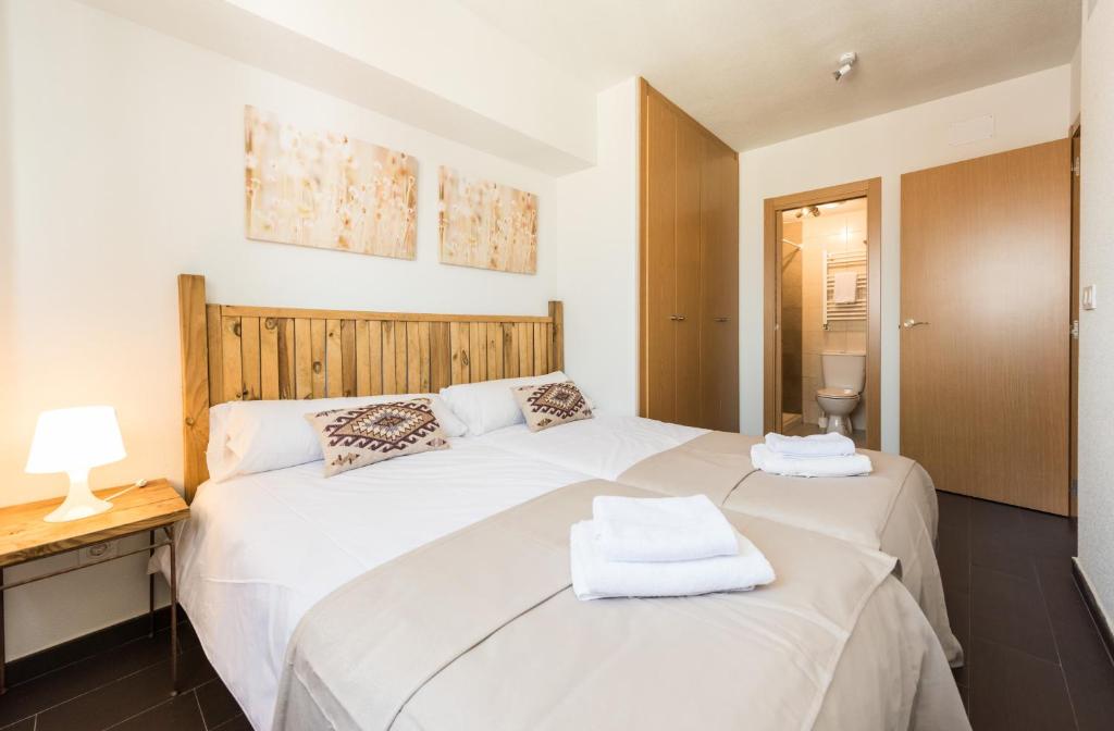 马德里马德里拉加塔公寓的卧室设有两张白色的床和木制床头板