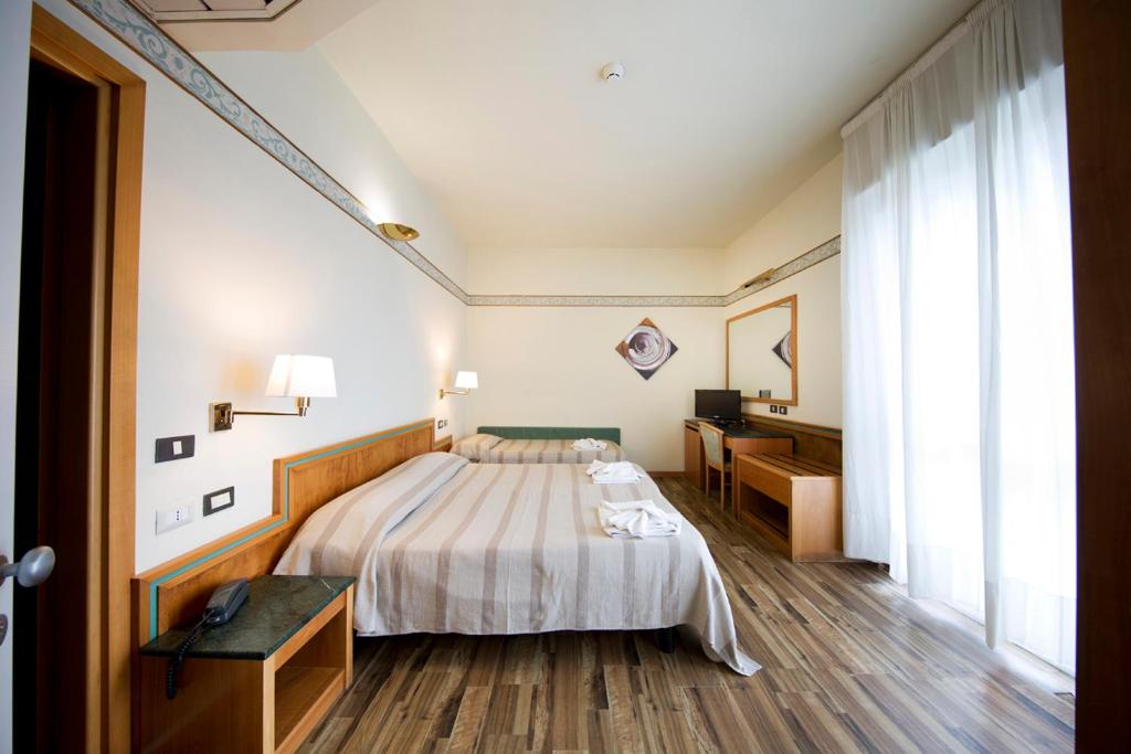 里米尼滨海湾酒店的配有一张床和一张书桌的酒店客房