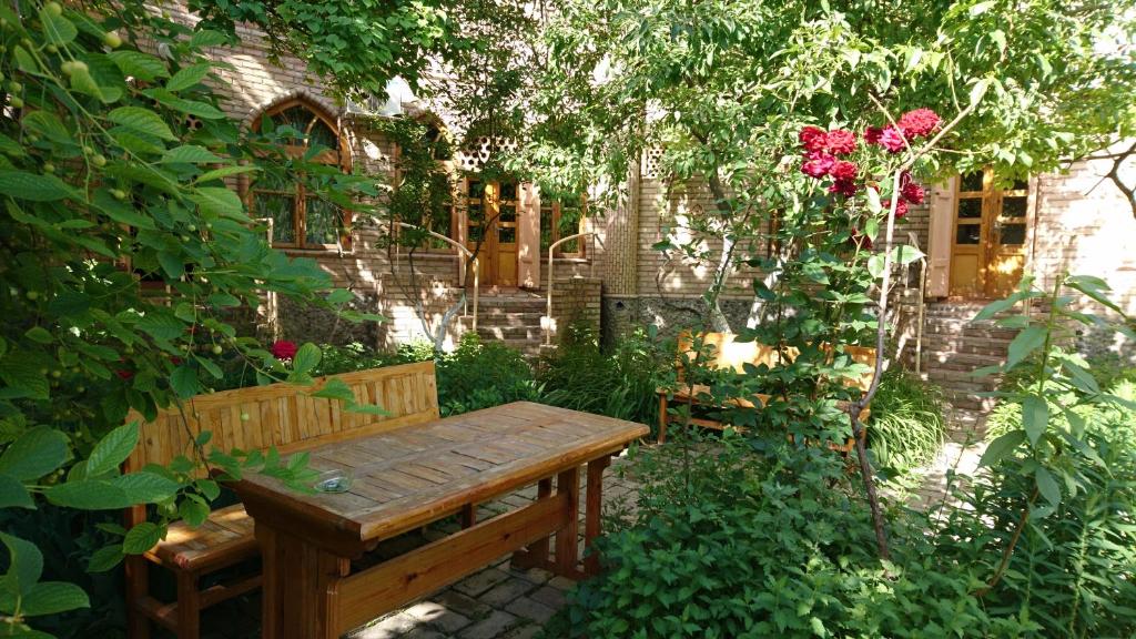 撒马尔罕ANTICA Family Guest House的坐在玫瑰园的木凳上