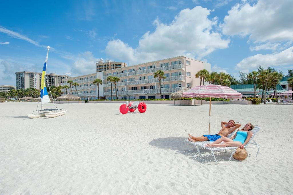 萨拉索塔丽都湾泳滩沙堡度假酒店的两人坐在海滩上一把遮阳伞下的椅子上