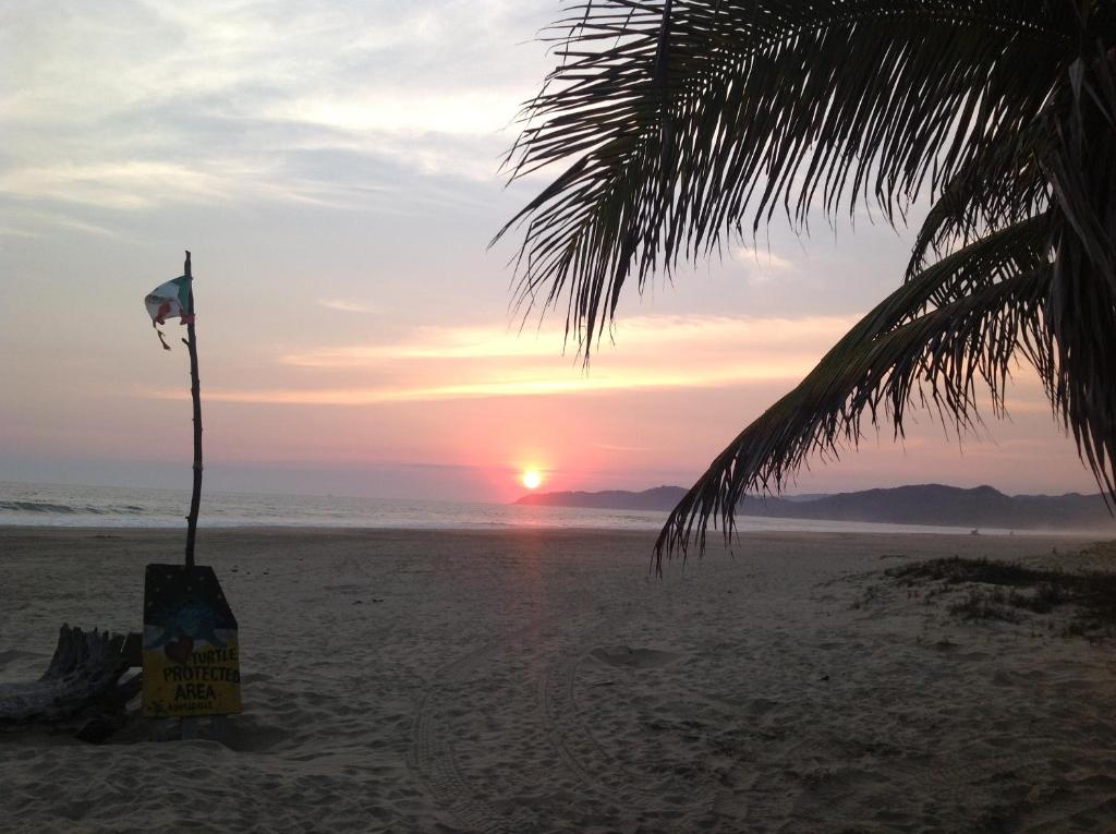 锡瓦塔塔内霍Casa de la Tortuga的沙滩上的日落,沙滩上挂着旗帜