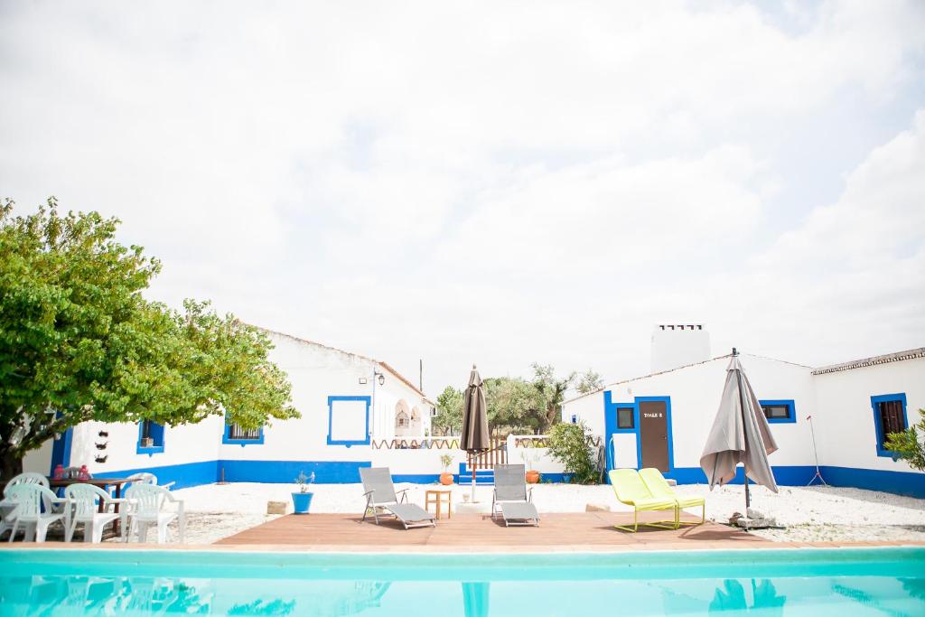 埃武拉Carrança Lounge的游泳池配有椅子、遮阳伞和桌子