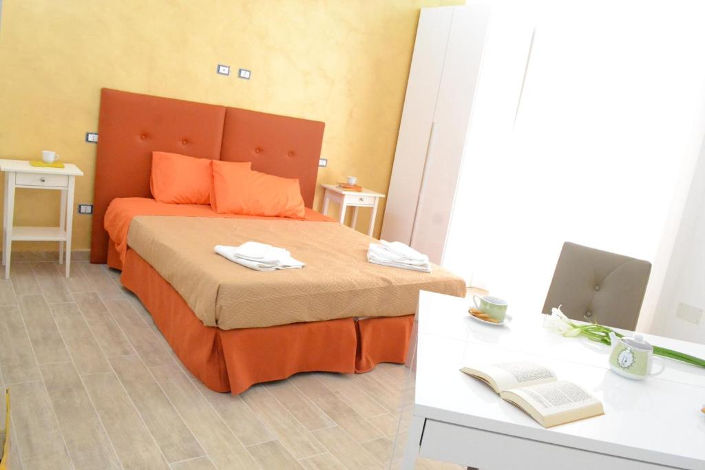 加利波利Il Cantastorie Salentino的一间卧室配有一张带橙色床头板的床和一张书桌