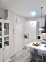 马德里Apartamento estilo nórdico en Malasaña (Madrid Centro)的厨房配有白色橱柜和一张摆着一碗水果的桌子