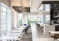 德斯坦Hyatt Place Sandestin at Grand Blvd的有白色桌椅和窗户的餐厅