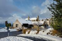皇后镇Rendezvous Heritage Hotel Queenstown的一个人在雪中走过房子