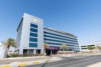 阿布扎比Premier Inn Abu Dhabi Airport Business Park的一座巨大的白色建筑，前面有棕榈树