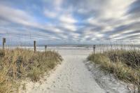 默特尔比奇Steps to Ocean Breezy Myrtle Beach Bungalow!的海滩上穿过沙滩的路径