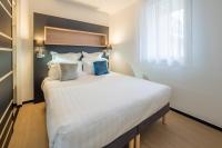 格勒诺布尔Apparthotel Le Hüb Grenoble的卧室里有一张大床，床单和枕头都是白色的