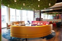 帕恩多夫ibis Styles Parndorf Neusiedler See的大堂设有黄色的等候室,配有桌椅