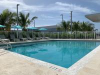 迈阿密Wyndham Garden Miami International Airport的度假村的游泳池，配有椅子和遮阳伞