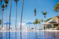 罗威那New Sunari Lovina Beach Resort的一座棕榈树、椅子和遮阳伞的游泳池