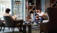 迪拜Revier Hotel - Dubai的三人坐在一个房间里,坐在椅子上,看着手机