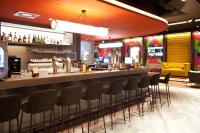 帕恩多夫ibis Styles Parndorf Neusiedler See的餐厅里的酒吧,周围摆放着椅子