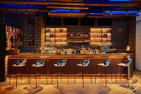 迪拜Revier Hotel - Dubai的砖墙前有凳子的酒吧