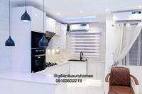 贝宁城Gillant Luxury Homes的厨房配有白色橱柜、水槽和椅子