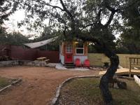 奥斯汀Fox Tiny Home - The Cabins at Rim Rock的一间小房子,有红色的门和红色的椅子