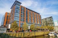 华盛顿InterContinental - Washington D.C. - The Wharf by IHG的一条高大的建筑物,旁边是一条有船的河流