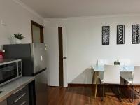 棕榈滩Palm beach Sydney, Modern home with water view的厨房配有微波炉和一张带白色椅子的桌子。