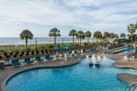默特尔比奇Courtyard by Marriott Myrtle Beach Oceanfront的海滩上的游泳池,带椅子和大海