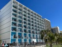 默特尔比奇Polynesian Oceanfront Hotel的一座巨大的白色建筑，前面有棕榈树
