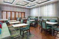 奥兰多汉普顿酒店 - 奥兰多机场村庄通道的有桌椅和窗户的餐厅
