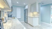 德斯坦Poolside Villas 106 - Updated beachfront condo on Holiday Isle in Destin的厨房设有蓝色的墙壁和白色的橱柜。