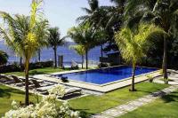 图兰奔Ocean View Tulamben Dive &amp; Resort的水边种有棕榈树的游泳池