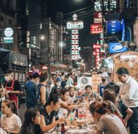 曼谷Qilombo Hostel Silom - HQ的一群人晚上坐在街上的桌子上