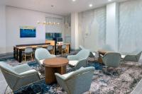 奥兰多Hyatt House Orlando Airport的一间设有椅子、一张桌子和一张书桌的等候室