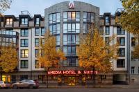 莱比锡Amedia Hotel &amp; Suites Leipzig, Trademark Collection by Wyndham的角形酒店和套房大楼前设有停车位