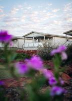 卡尔巴里Kalbarri Red Bluff Tourist Park的一座在前面布满紫色花的建筑