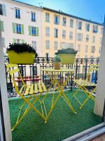 尼斯Cœur d&#39;Azur Appartement的阳台配有两把椅子和一张桌子,阳台与大楼相连