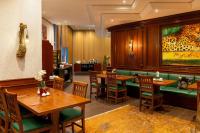 莱比锡Amedia Hotel &amp; Suites Leipzig, Trademark Collection by Wyndham的有木桌和绿色椅子的餐厅