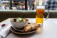 曼彻斯特Malacuna Manchester的一碗食物、一碗沙拉和一杯啤酒