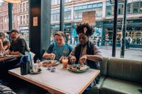 曼彻斯特Malacuna Manchester的一群人坐在桌旁吃饭