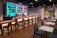 纽约Hampton Inn by Hilton New York Times Square的餐厅内的酒吧配有木桌和椅子