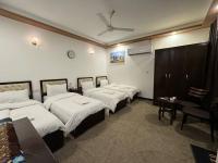 巴格达SAFIR BAGHDAD HoTEL的一间有四张床的酒店房间，墙上挂着一个钟