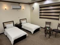 巴格达SAFIR BAGHDAD HoTEL的一间有两张床、一张桌子和几把椅子的酒店房间